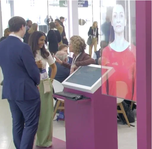 Conference attendees trying a touchscreen beside a life-size digital presenter
